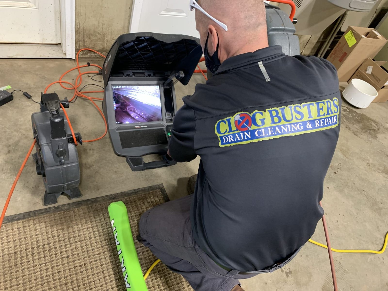 Clog Busters technician crouched at a sewer camera inspection monitor