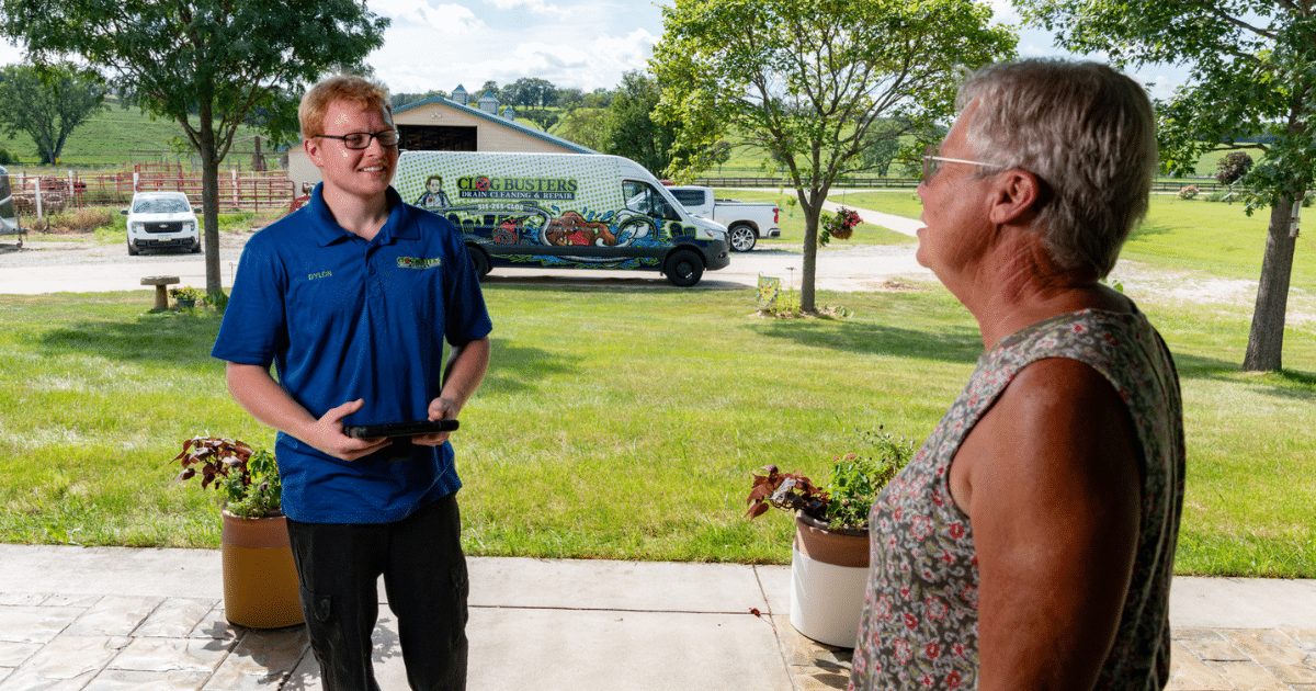 Clog Busters technician talking with a homeowner beside the service van