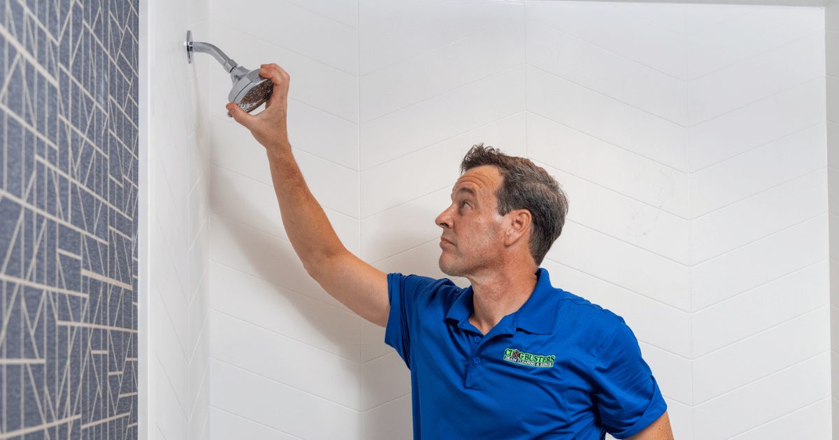 Clog Busters technician servicing a shower valve in a tiled bathroom